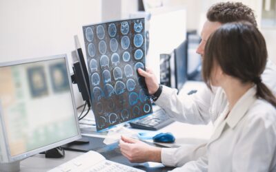 two doctors, a man and a woman, examine an MRI image of the brain