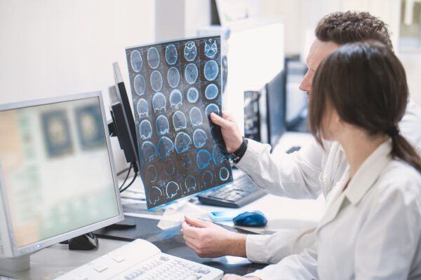 two doctors, a man and a woman, examine an MRI image of the brain