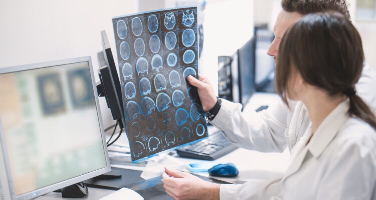 two doctors, a man and a woman, examine an MRI image of the brain