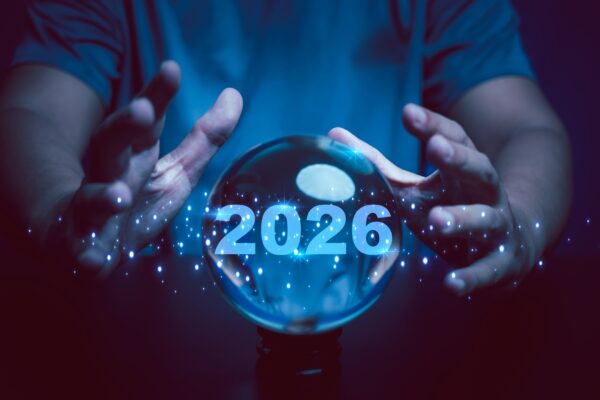 A pair of hands around a crystal ball that has the year 2026 written inside it.